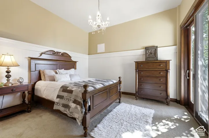 Carpeted room featuring wainscoting, a sliding glass door, and a decorative chandelier