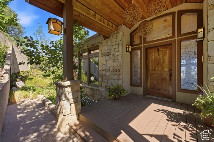 Rustic wood-finish porch featuring a paneled entry door, adjacent sidelights, and stone veneer accents
