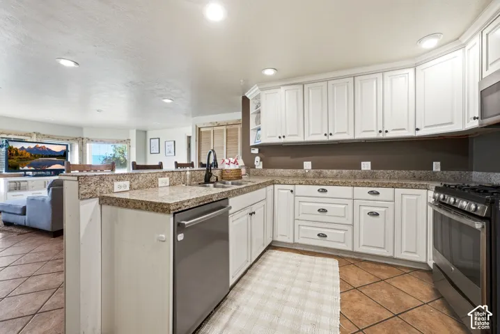 Kitchen featuring white cabinetry, granite-finish countertops, stainless steel appliances, and tile flooring