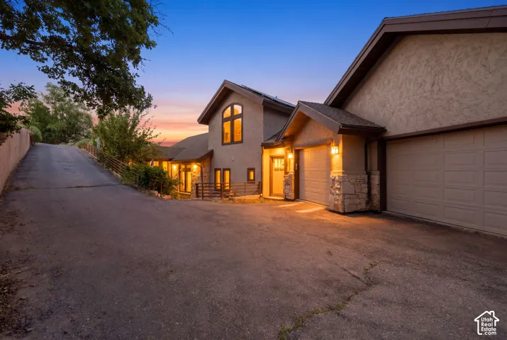 Stucco exterior featuring multiple garages, stone accents, and a distinctive arched window