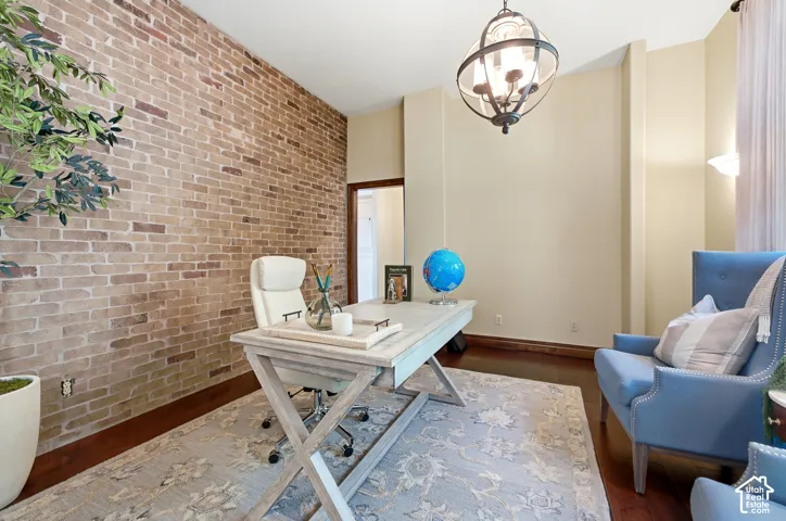 Exposed brick accent wall, dark wood-finish flooring, recessed wall lighting, and an ornate ceiling fixture