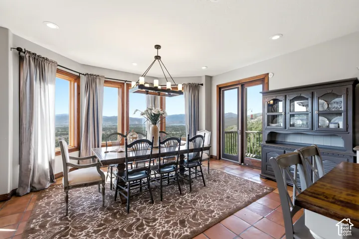Dining area featuring terracotta flooring, a dark wood dining table, and a linear chandelier