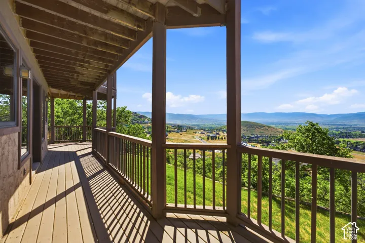 Expansive outdoor deck featuring wood-finish flooring, a covered ceiling, and a sturdy wood railing