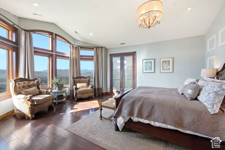 Spacious room featuring wood-finish flooring, a curved wall of large windows, and a double French door leading to an exterior balcony