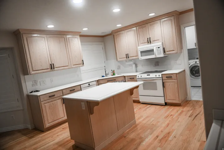Kitchen featuring light wood cabinetry with dark hardware, white countertops, and a subway tile backsplash