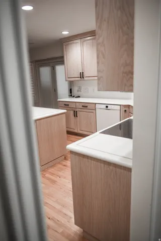 Kitchen featuring light wood-finish cabinetry with dark hardware, white countertops, built-in dishwasher, and recessed lighting