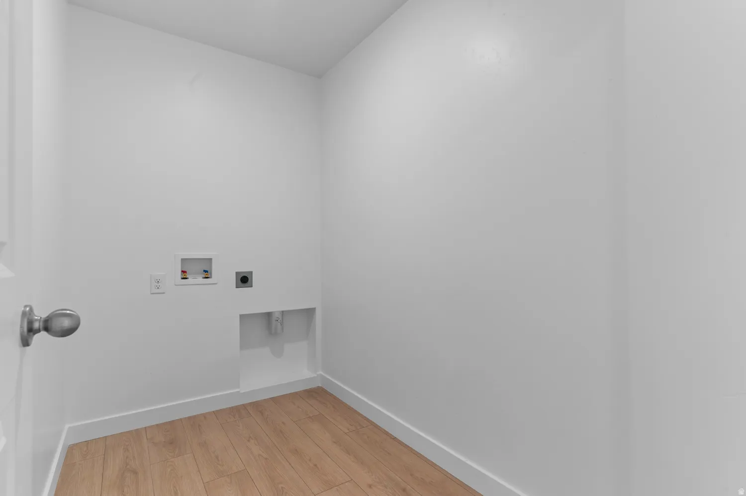 Dedicated utility space featuring light wood-finish flooring, white walls, and bright white trim