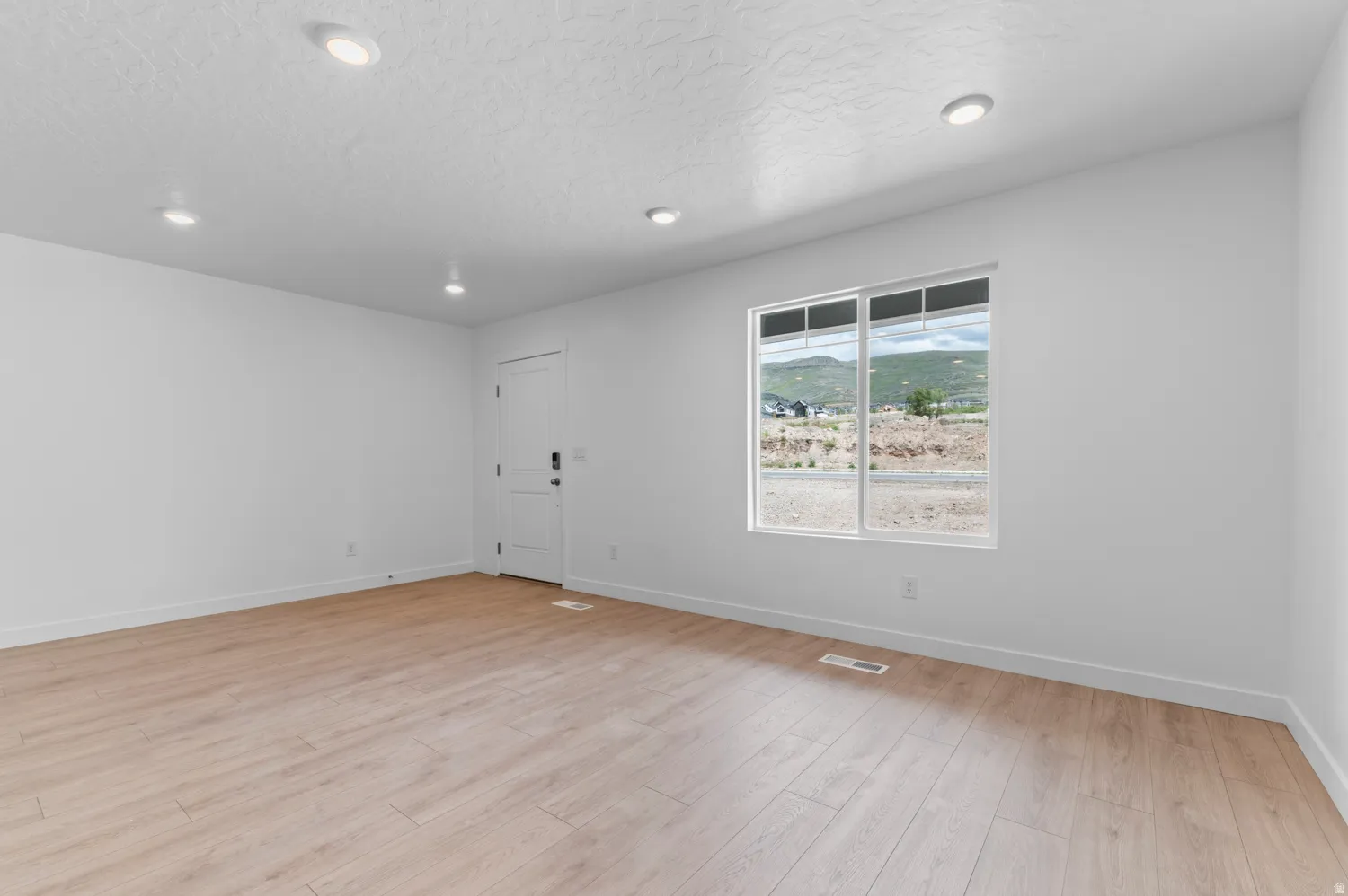 Spacious room featuring wood-finish flooring, white walls, and recessed lighting