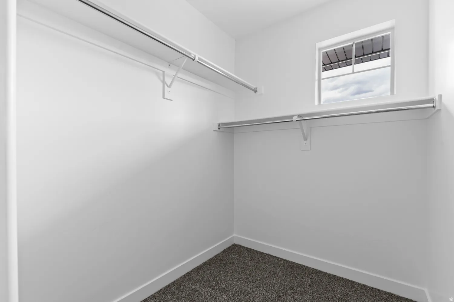 Walk-in closet featuring built-in shelving, hanging rods, and a window for natural light