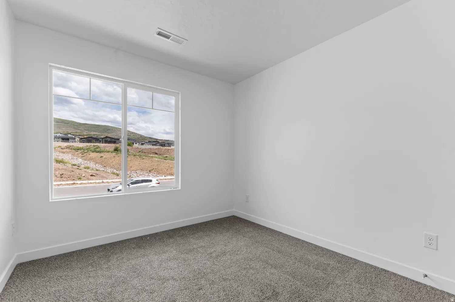 Room featuring a large window, neutral carpeting, white walls, and white baseboards