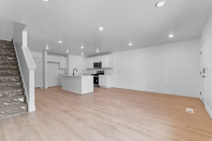 Open-concept living space featuring wood-finish flooring, recessed lighting, and a modern kitchen with a center island