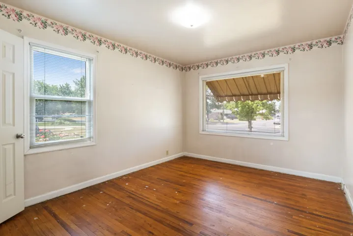 Wood-finish flooring throughout, featuring two windows with blinds, and white trim