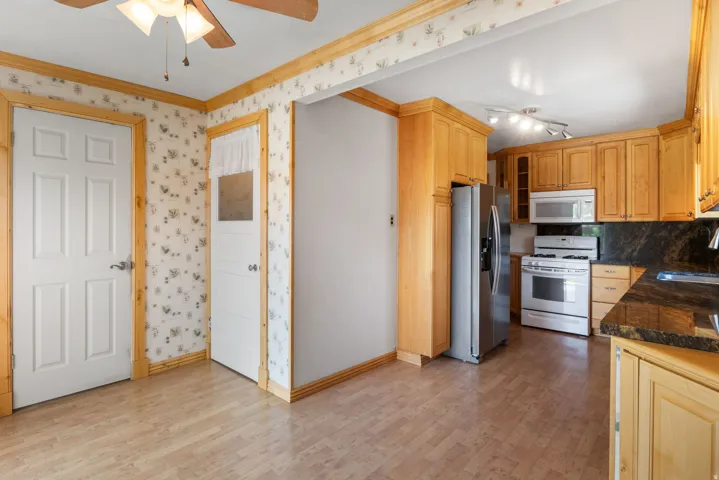 Kitchen featuring wood-finish flooring, natural wood cabinetry, stainless steel refrigerator, white range, and microwave