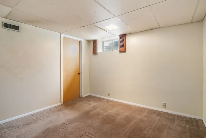 Carpeted room with a drop ceiling and light-colored walls