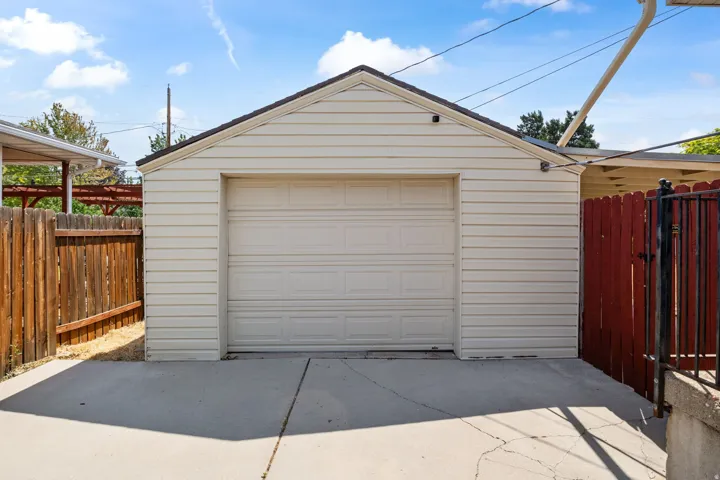 Detached garage featuring a paneled door, light-colored siding, and a gabled roofline