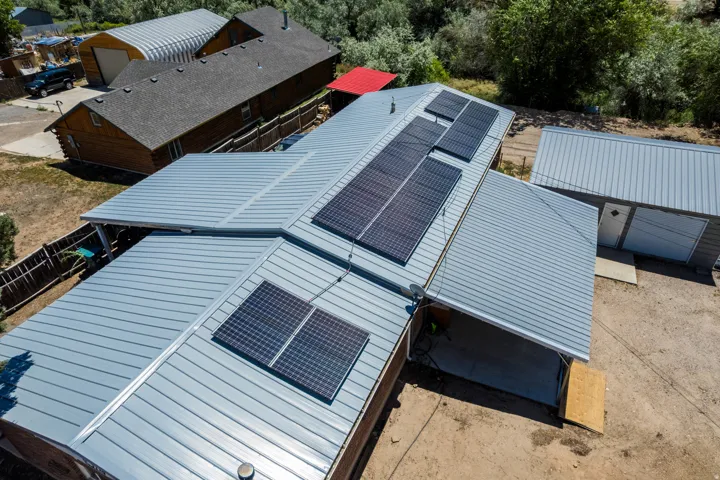 Property featuring multiple solar panels, a light grey metal roof, and an attached carport