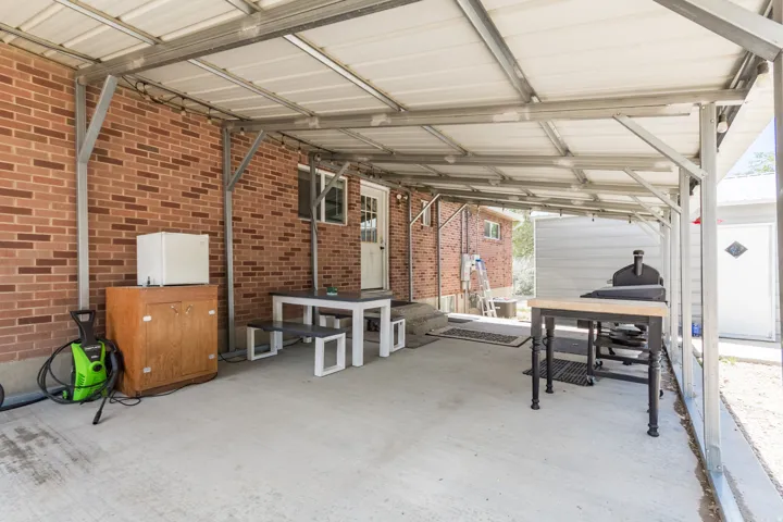 Covered patio space featuring a concrete slab, metal frame awning, and a brick exterior wall