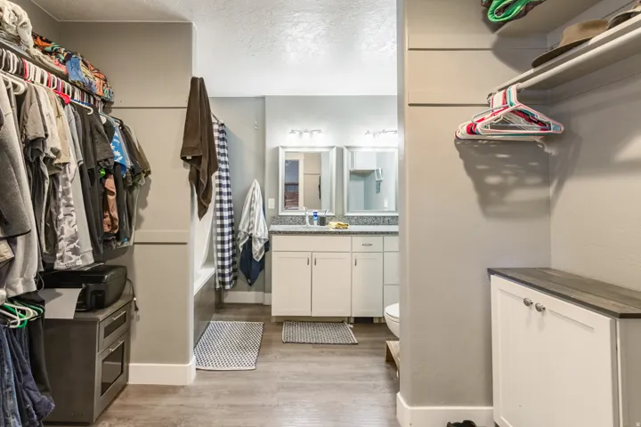 Bathroom featuring a dual vanity with granite-finish countertops, white cabinetry, and individual framed mirrors