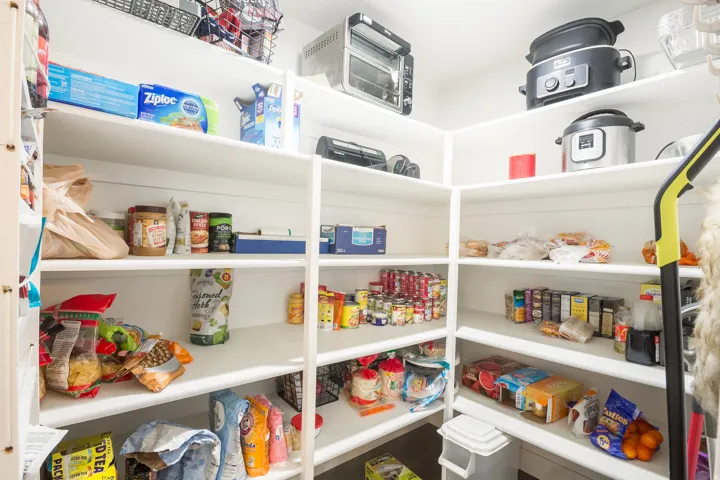 Expansive pantry featuring multiple levels of built-in shelving, white finishes, and ample storage capacity