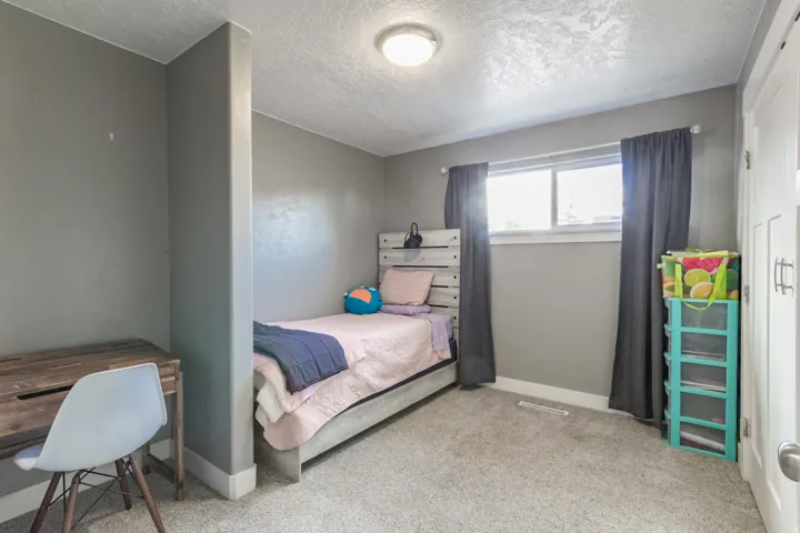 Carpeted room featuring a built-in partial wall, a window with a white frame, and a white interior door with contemporary hardware