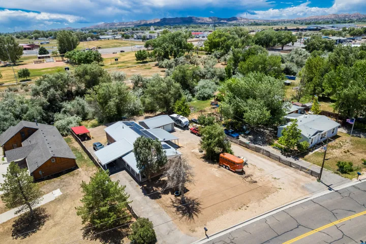 Aerial perspective showcasing multiple properties, including a residence with solar panels and an attached carport