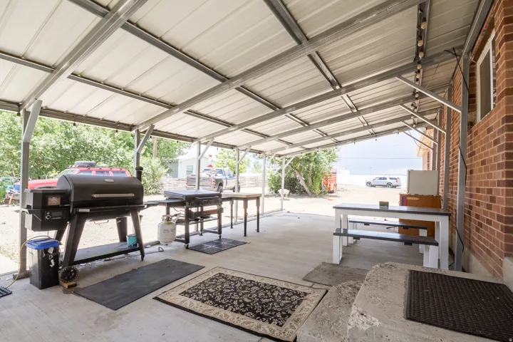 Spacious covered patio featuring a metal roof structure, string lighting, and a concrete slab foundation