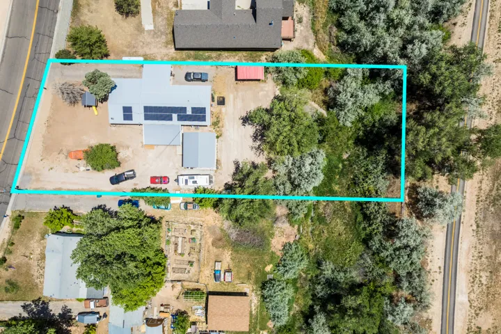 Expansive property featuring a main residence with a light gray roof, multiple solar panels, and a detached structure