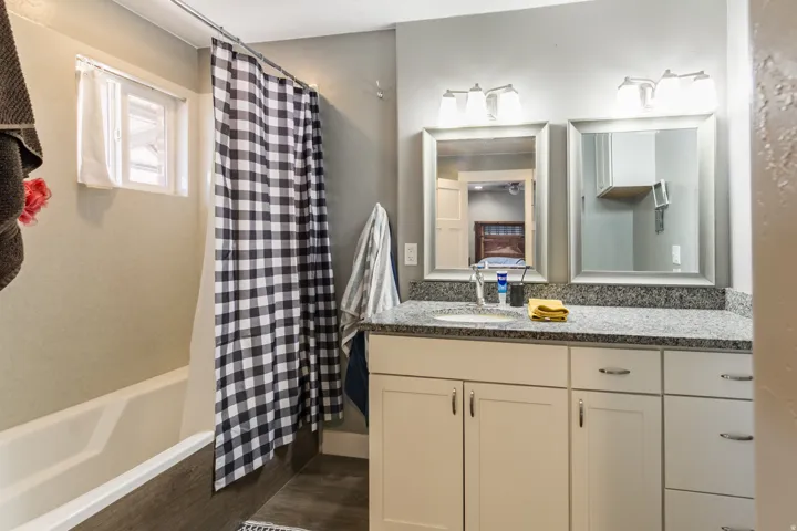Bathroom featuring a double vanity with granite-style countertops, dual framed mirrors, and white cabinetry with brushed nickel hardware
