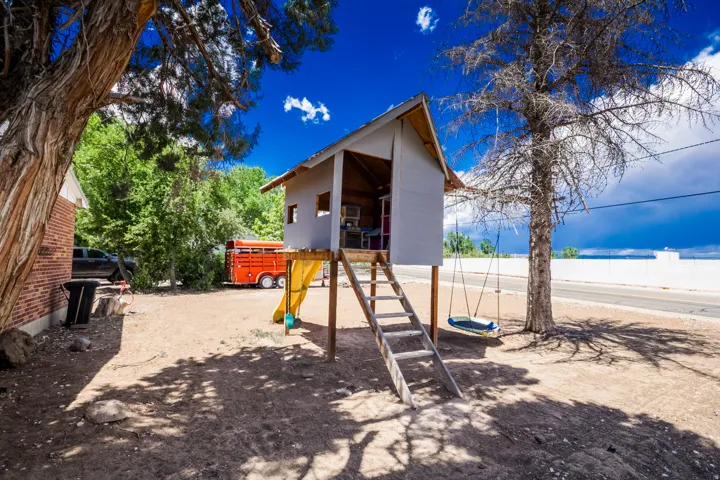 Backyard play structure featuring an elevated house, wood ladder access, and an attached yellow slide