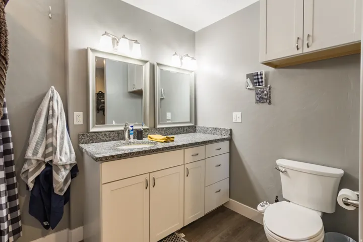 Vanity featuring dual framed mirrors, a light granite countertop, and white cabinetry