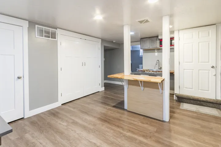 Open-concept area featuring wood-finish flooring, a breakfast bar with a light wood countertop, white trim throughout, and recessed lighting