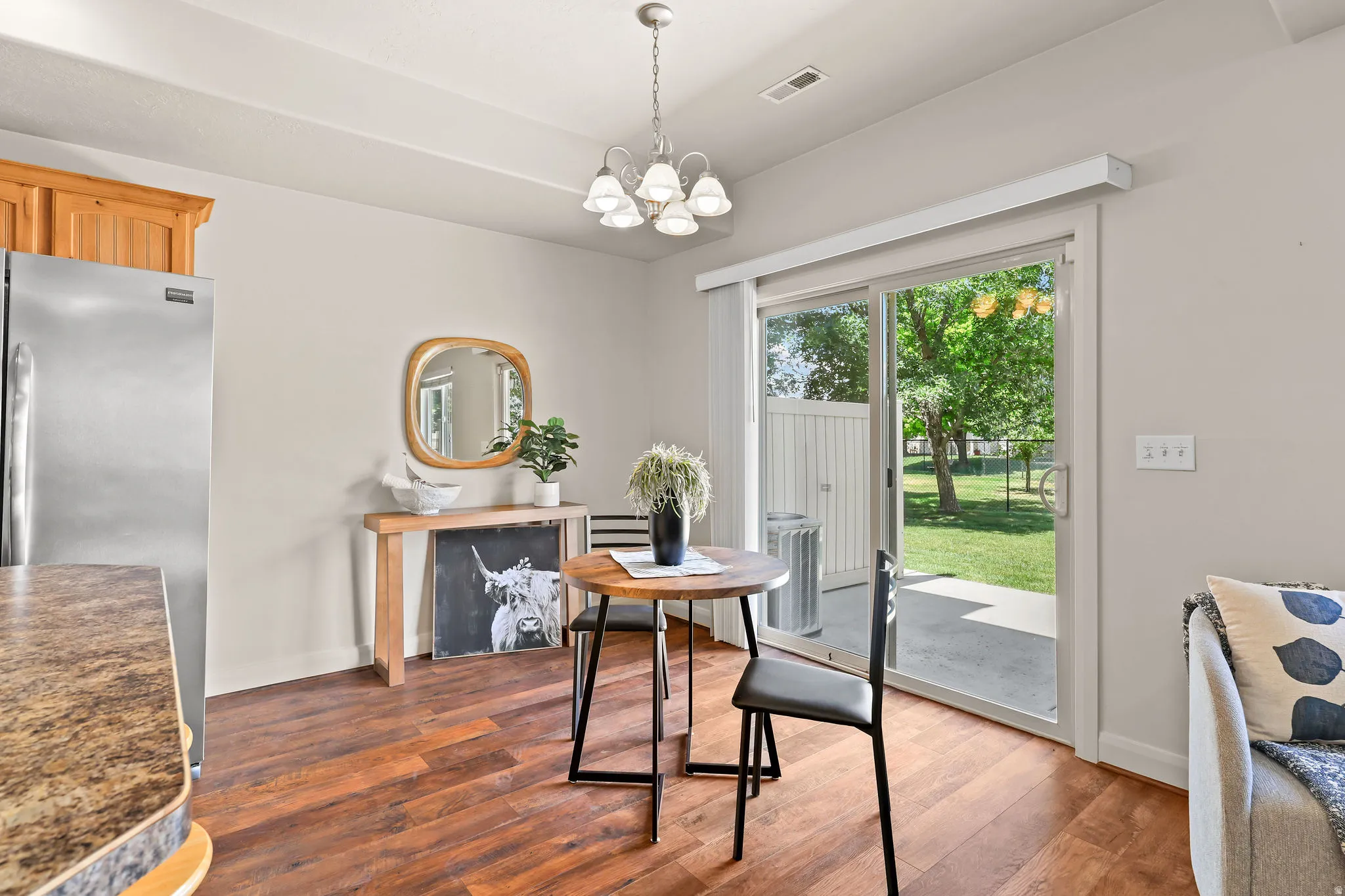 Dining area featuring laminate wood flooring, a contemporary chandelier, and direct patio access through sliding glass doors