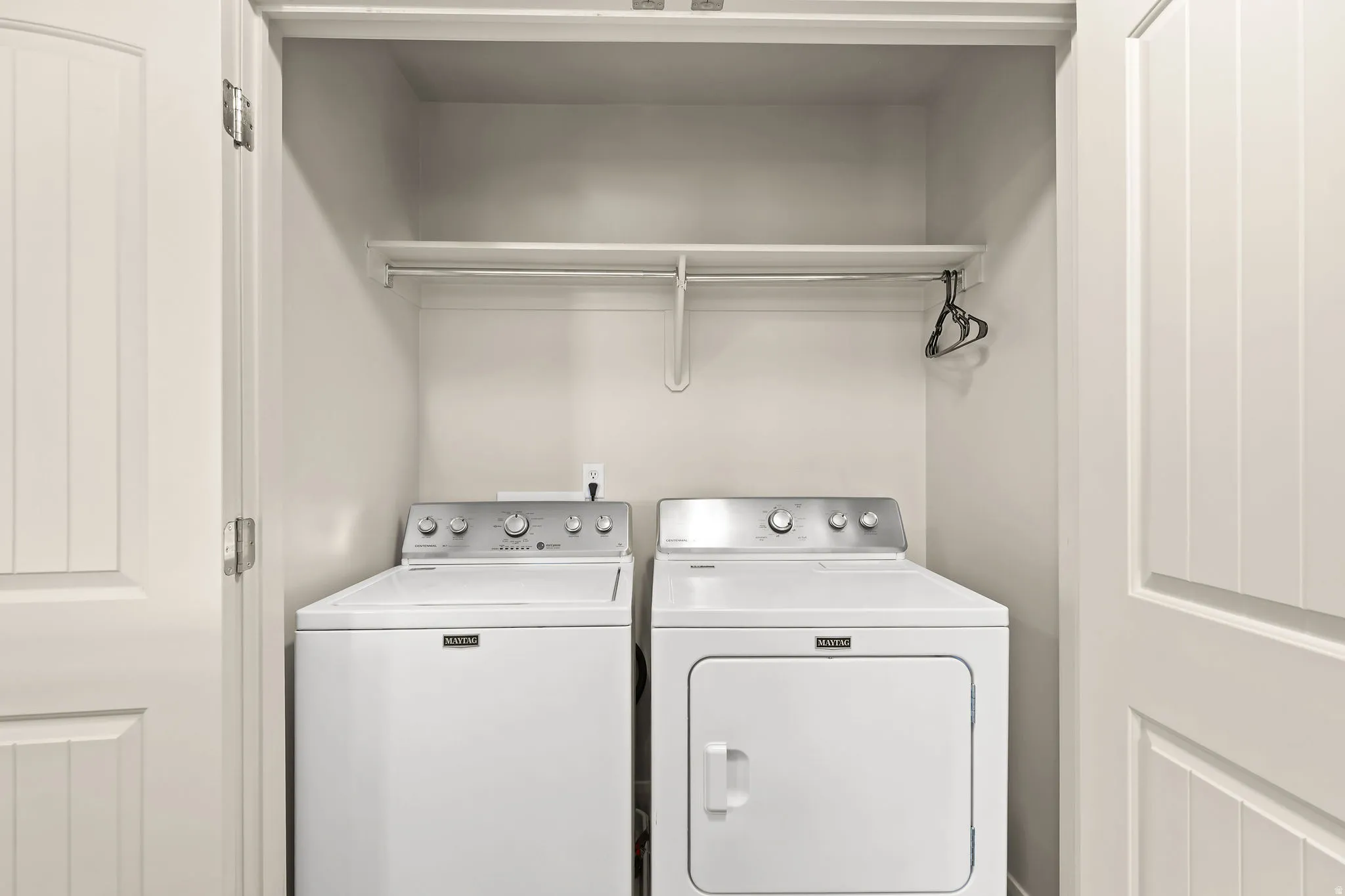 Dedicated laundry closet featuring a top-load washing machine, front-load dryer, upper shelf, and hanging rod