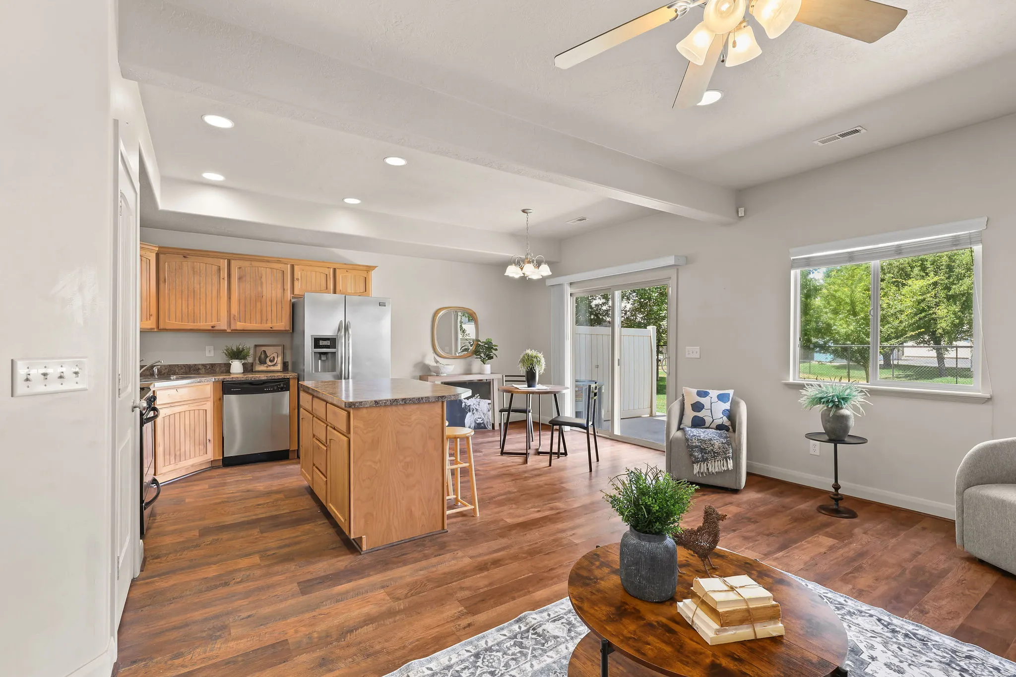 Open-concept living area with wood-finish flooring, a kitchen island with seating, and stainless steel appliances