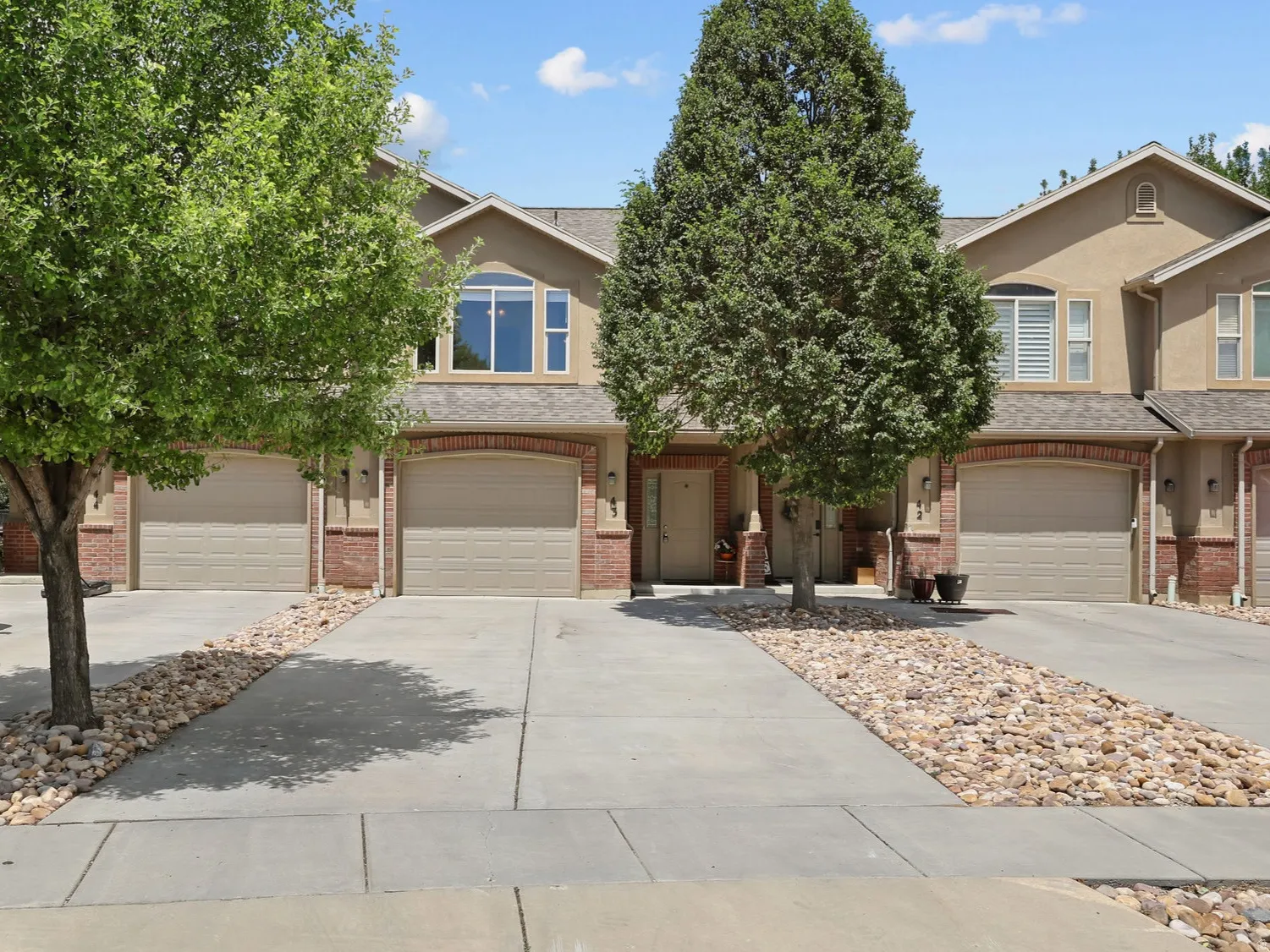 Two-story home featuring a stucco facade with brick accents and arched garage entries
