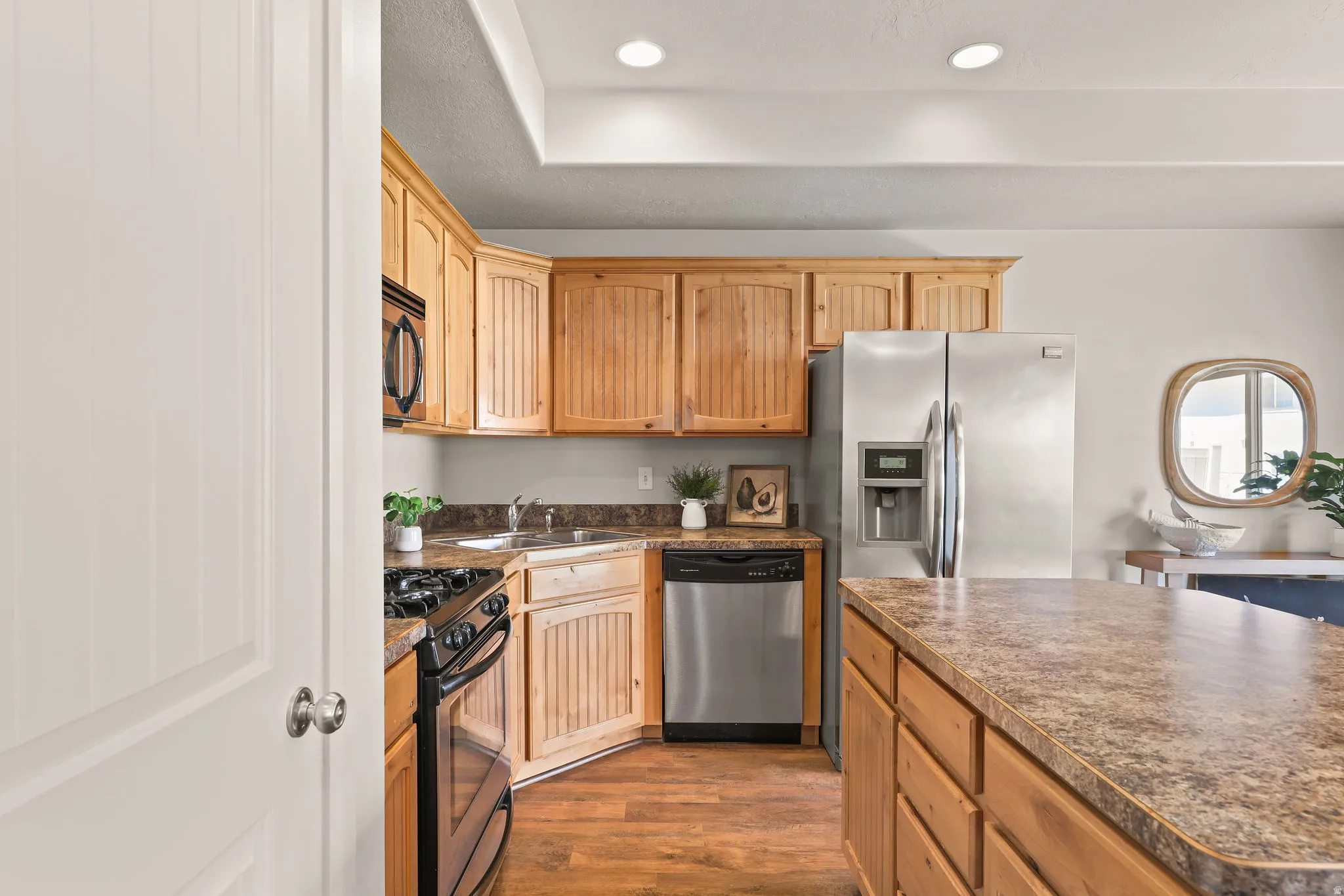 Kitchen featuring wood cabinetry, stainless steel appliances, speckled countertops, wood-finish flooring, and recessed lighting