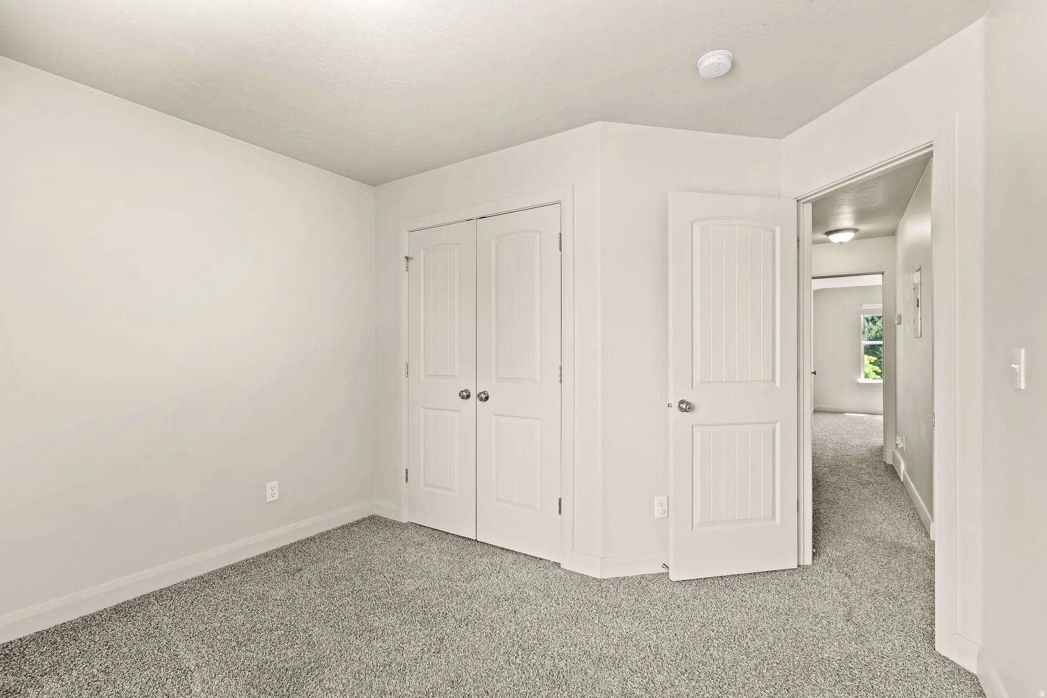 Carpeted room with a double-door closet and white trim