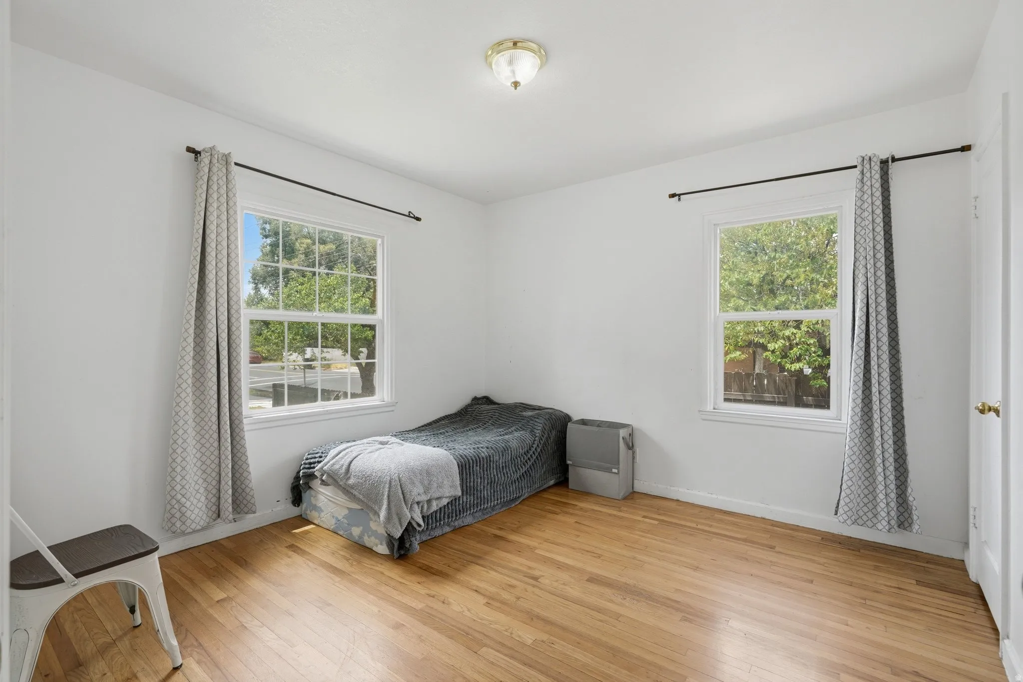 Bedroom #1 Bright interior space featuring wood-finish flooring, white walls, and two multi-pane windows