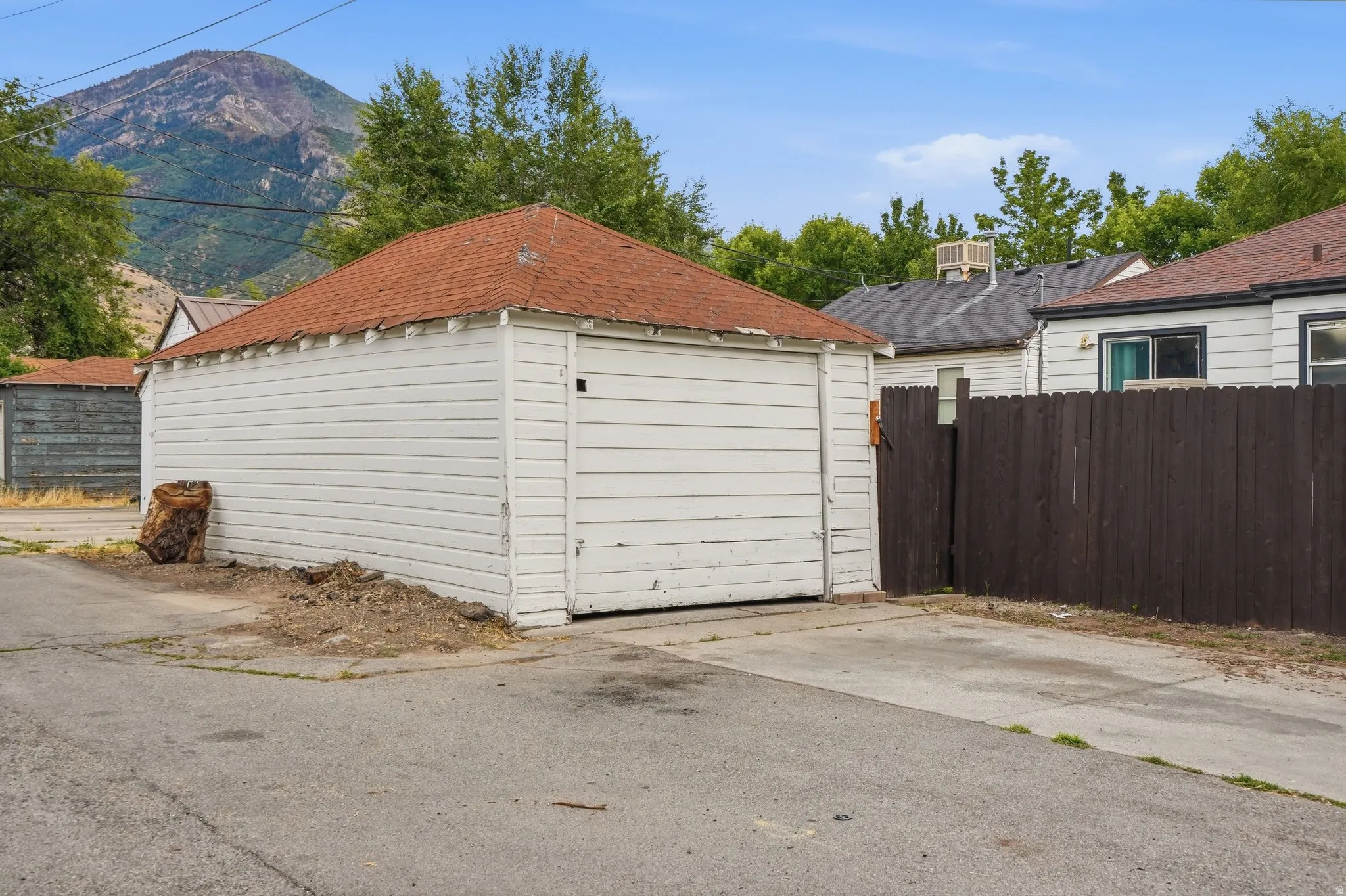 Detached garage with horizontal white siding and a red shingle roof