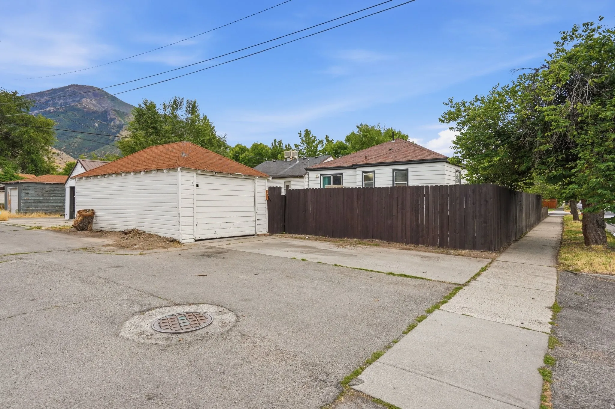 Detached garage building with white siding and a brown shingle roof