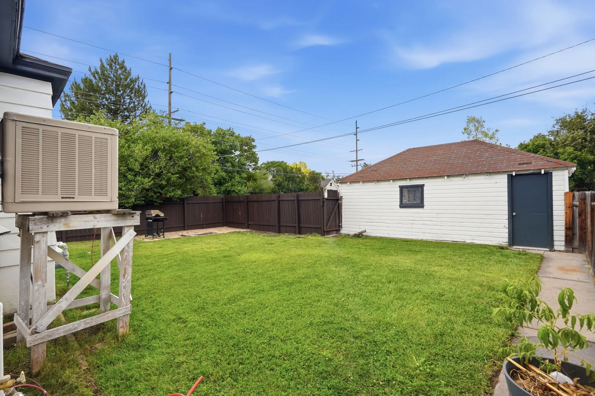 Expansive fenced backyard featuring a detached garage with a dark-paneled door, a brown shingle roof, and a concrete walkway