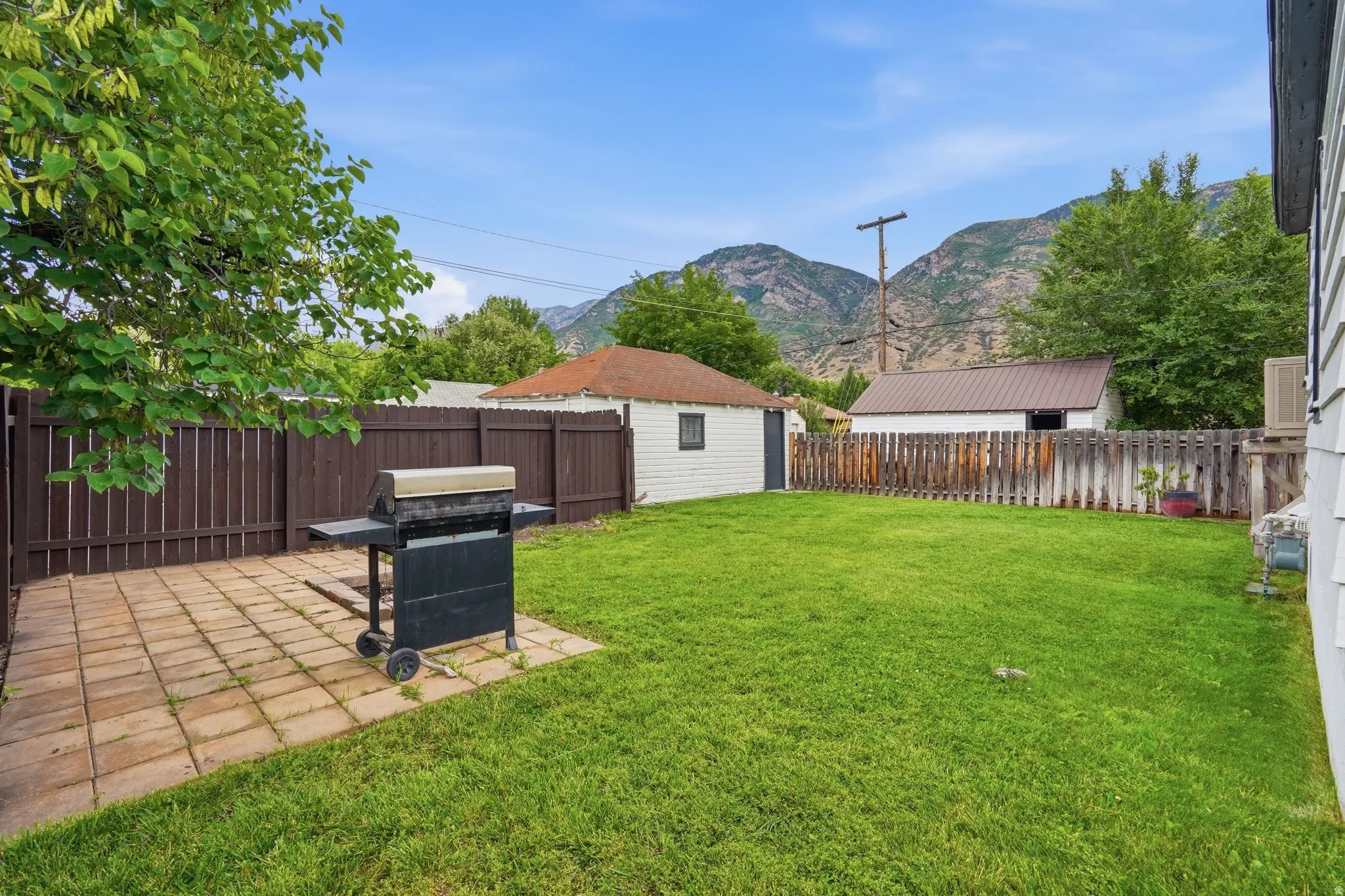 Expansive backyard featuring a lush lawn, a paved patio area, and a privacy fence