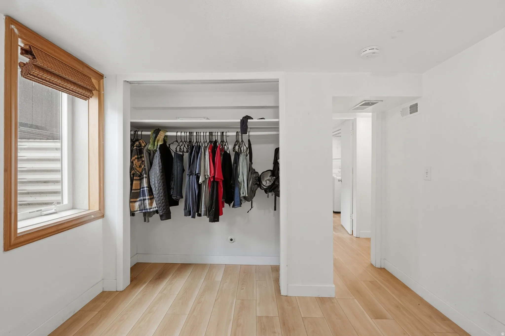 Bedroom #4 Interior room featuring light wood-finish flooring, white walls, and a recessed clothing closet with hanging rod