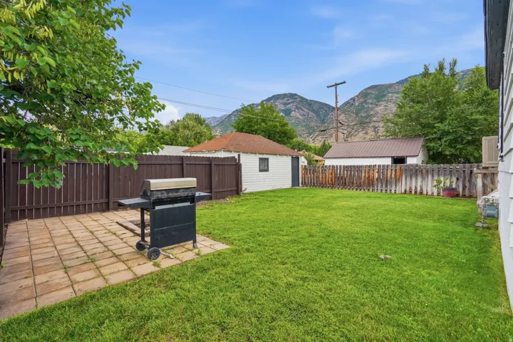 Expansive backyard featuring a lush lawn, a paved patio area, and a privacy fence