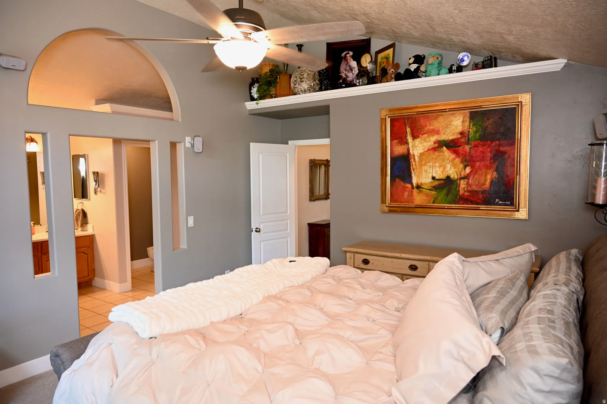 Bedroom with an arched transom, a ceiling fan with light fixture, and an integrated shelf
