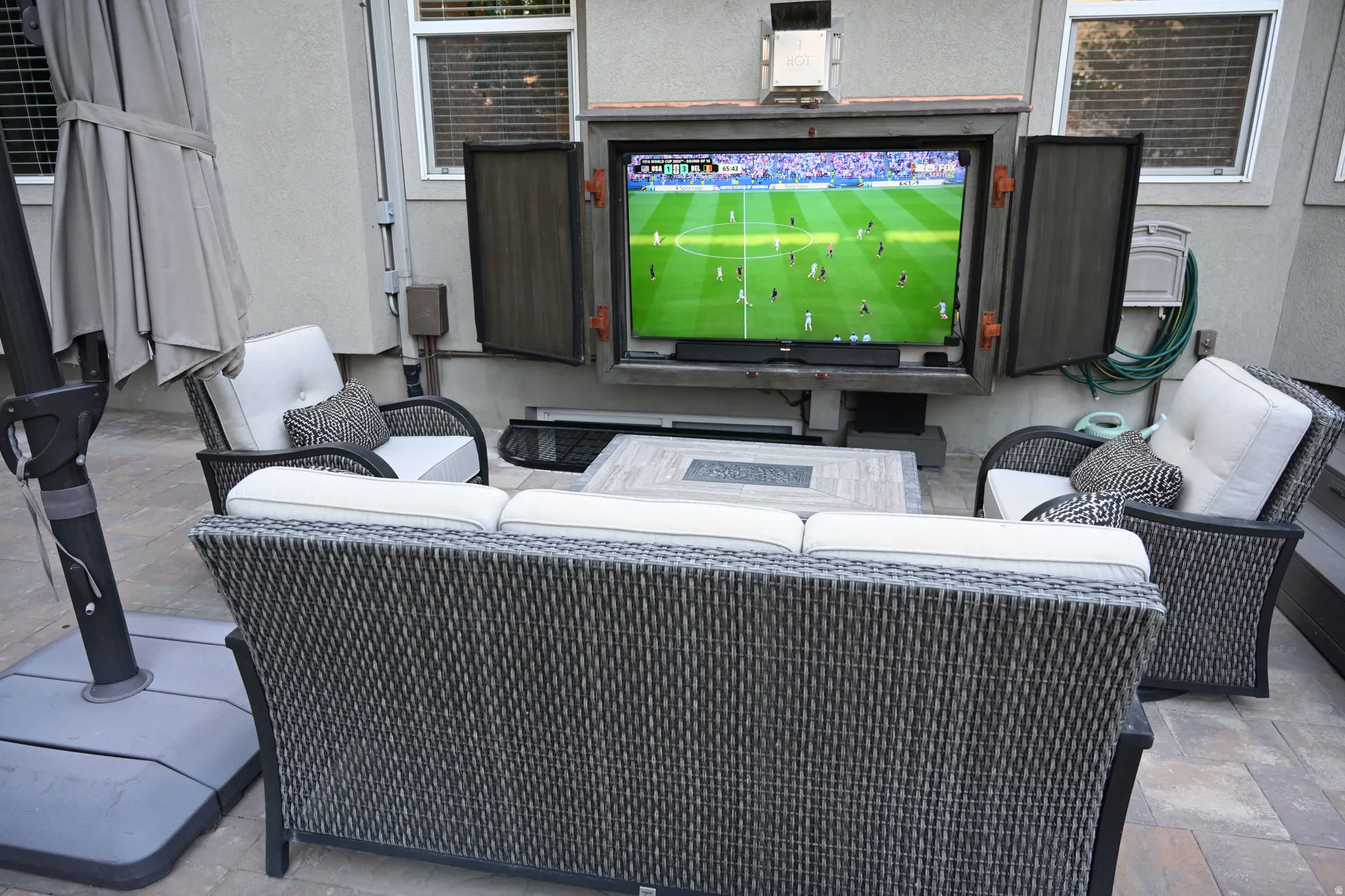 Outdoor entertainment area featuring a mounted television in a protective enclosure