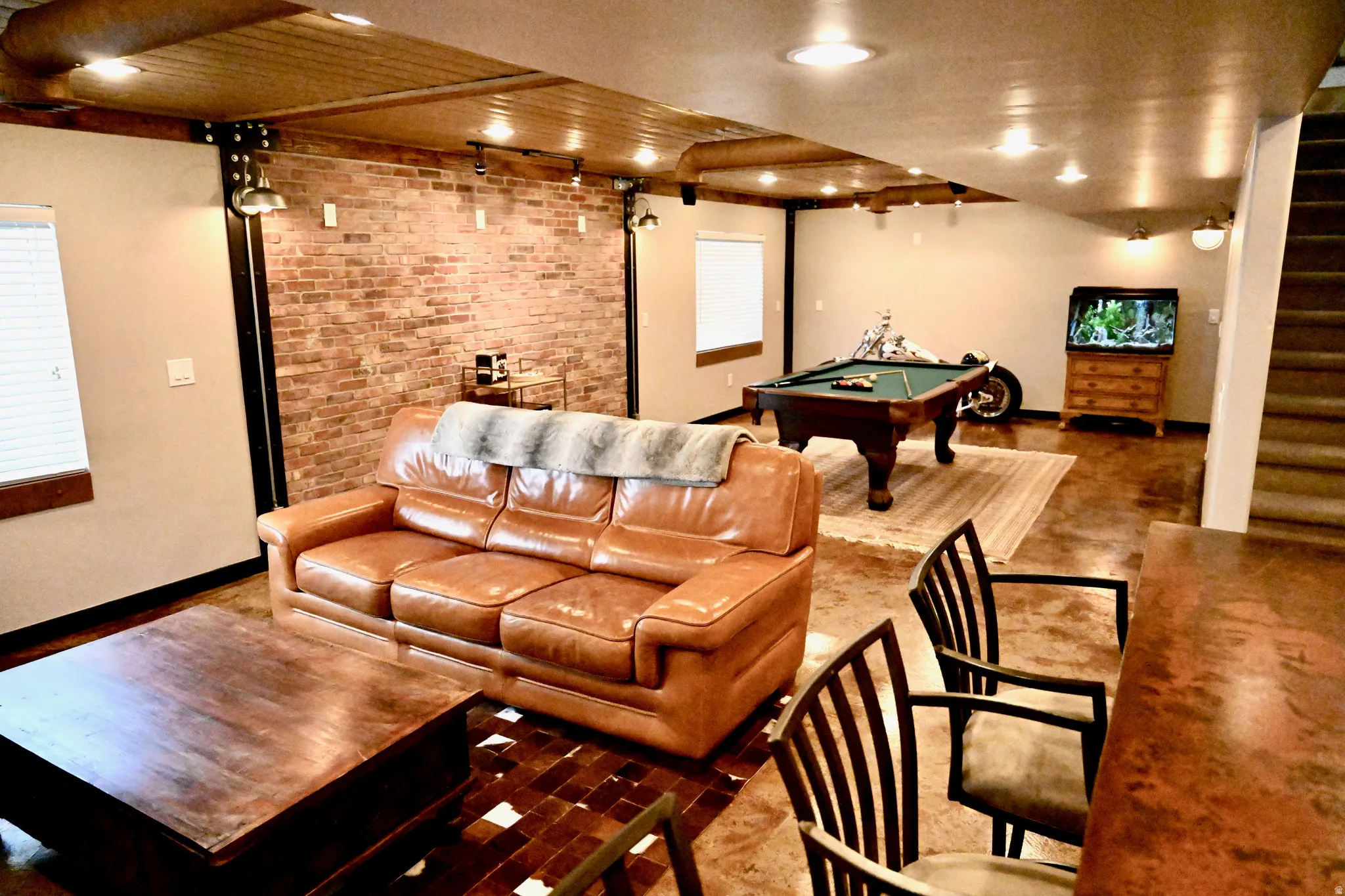 Exposed brick accent wall and wood-finish ceiling with recessed and track lighting