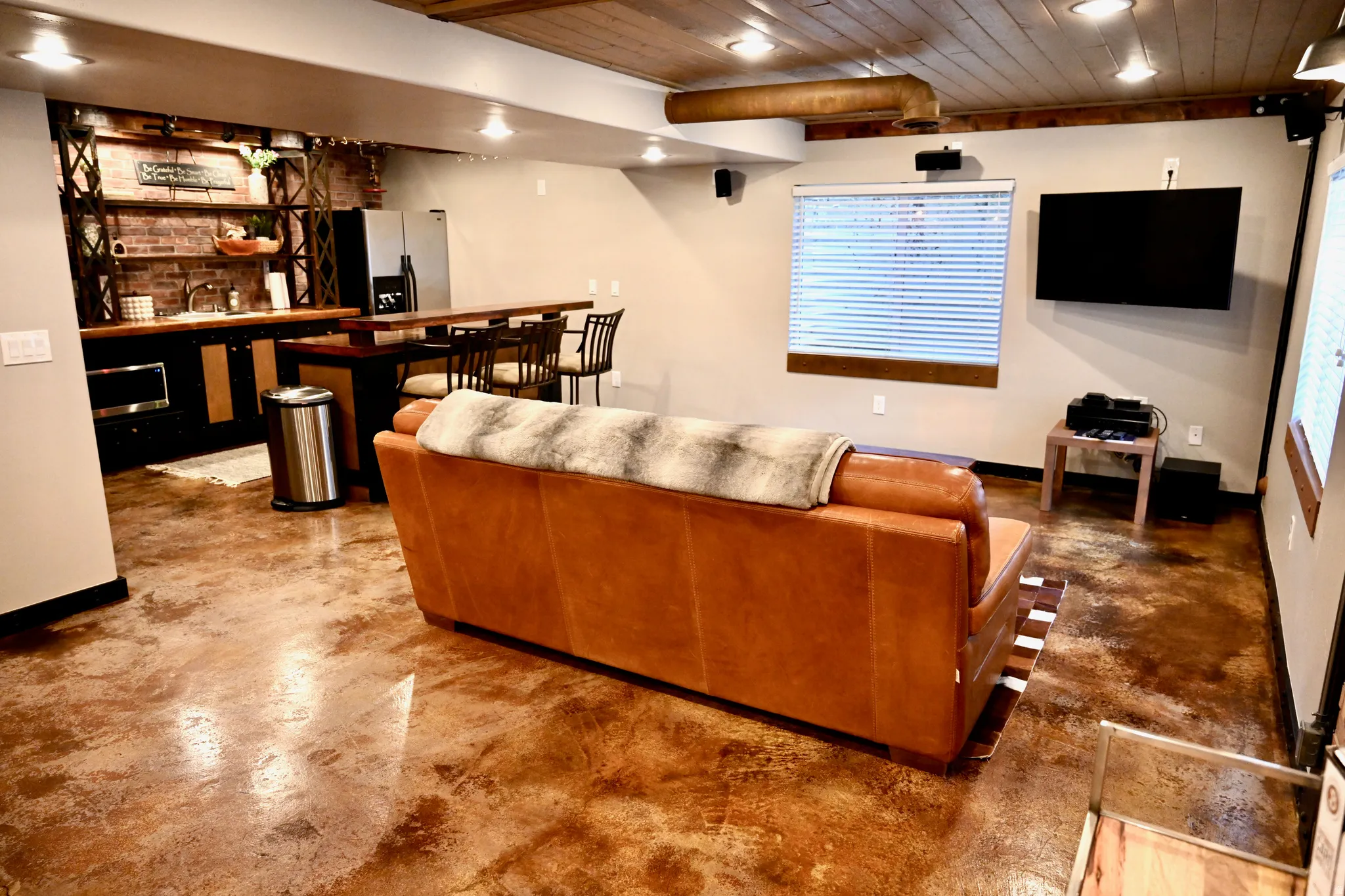 Open-concept entertainment space featuring unique multi-toned flooring, a wood-paneled ceiling, and recessed lighting