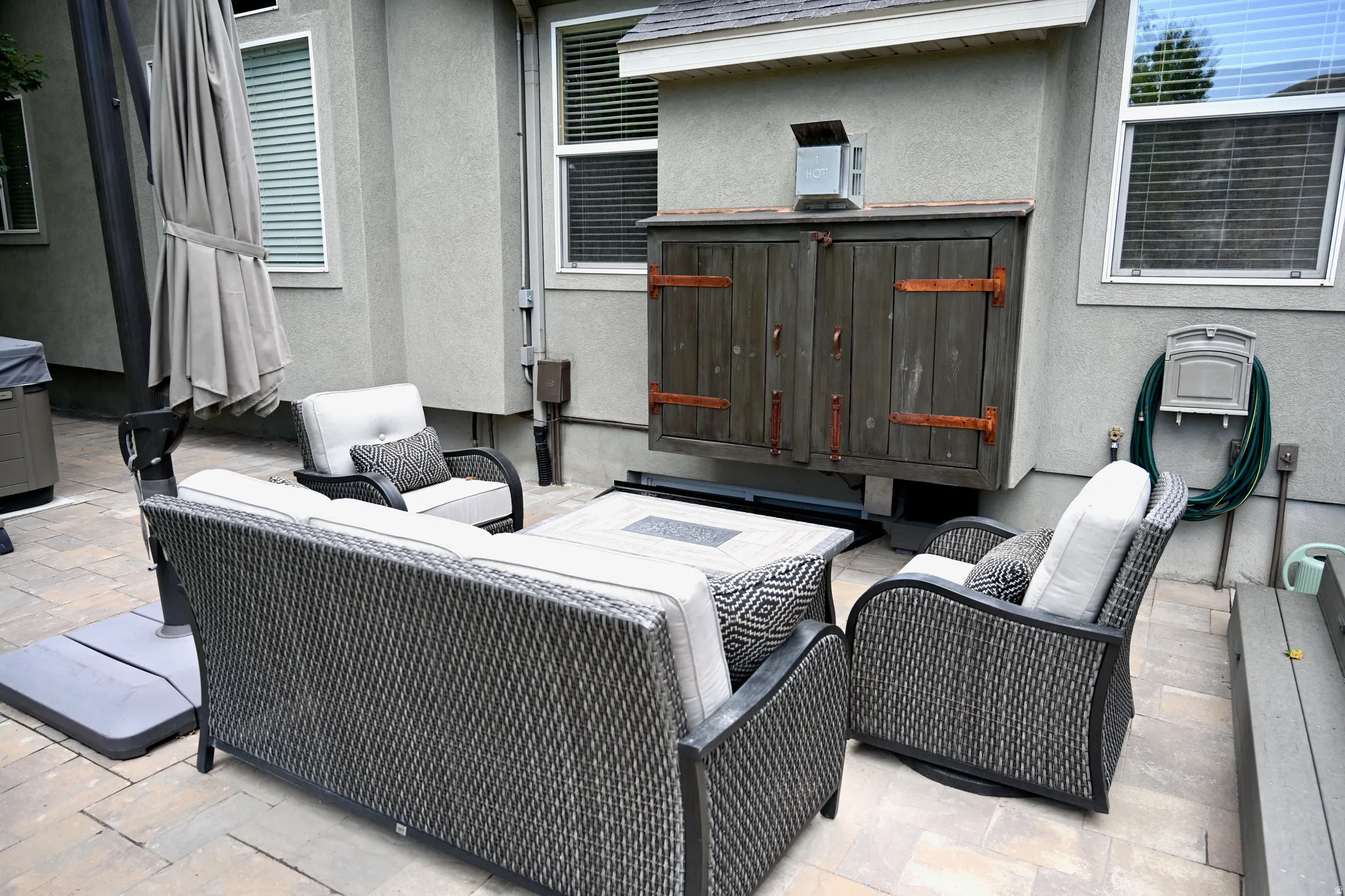 Stone paver patio featuring a built-in outdoor cabinet with distressed wood doors
