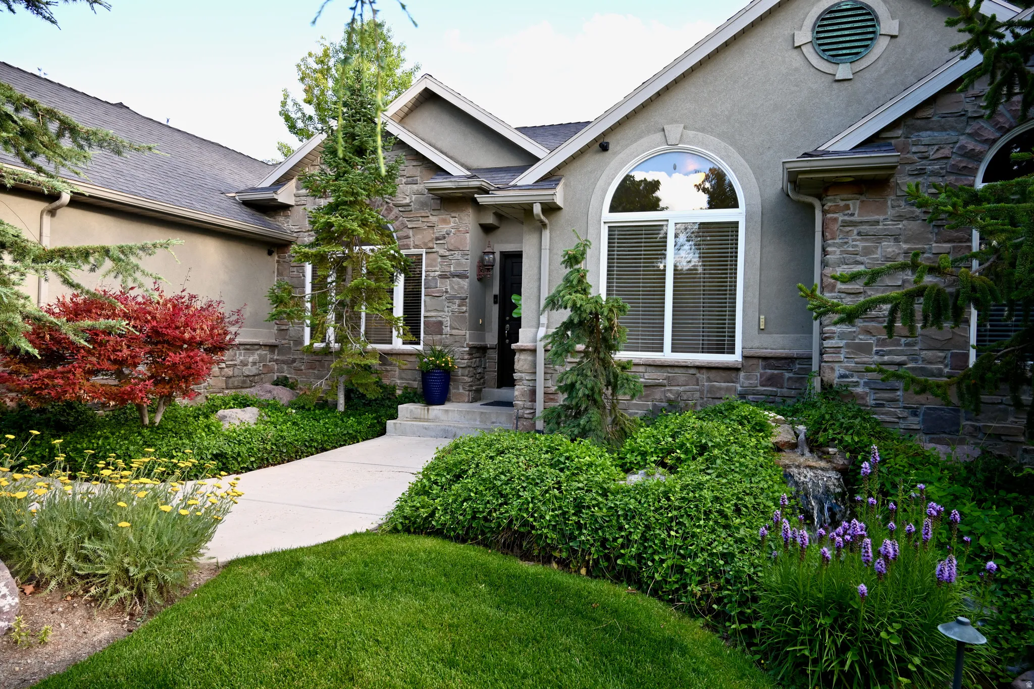 Stucco and stone exterior featuring an arched window and a decorative circular vent